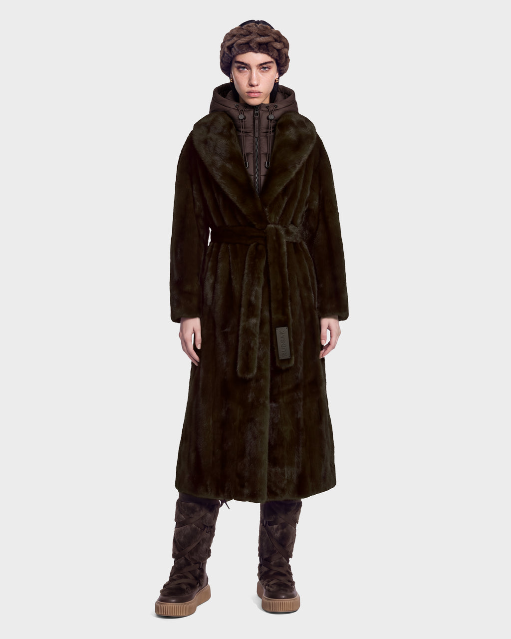 A person wearing a long, belted dark green faux fur coat over a duck down jacket, styled with a braided dark brown headpiece and Rudsak VIVIENNE - 8126528 Espresso lace-up boots for winter city dressing.