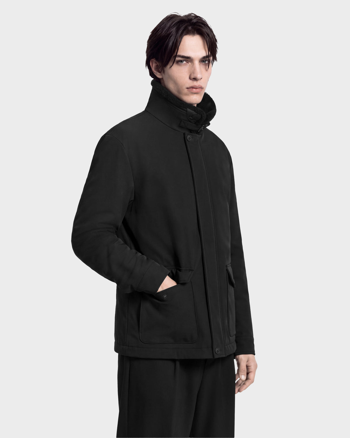 A man wearing the black ANTOINE - 6126506 Rudsak utility jacket with a funnel neck and front patch pockets.