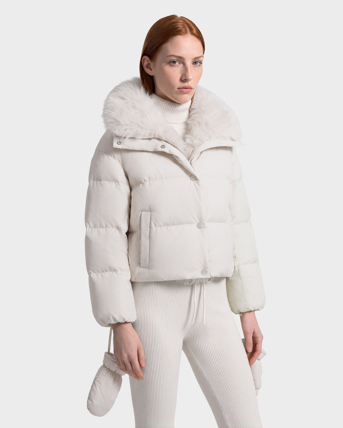 Rudsak ALONDRA - 8126992 Vanilla cropped, cream-colored puffer jacket with a large faux fur collar worn over a matching ribbed turtleneck and leggings; an essential piece of winter outerwear.