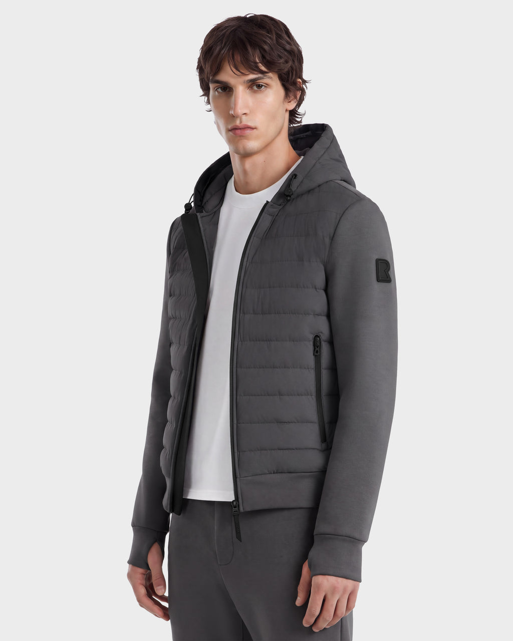 A man wears a grey Rudsak DEE MAT - 6124028 lightweight hybrid down jacket with a quilted front panel over a white t-shirt.