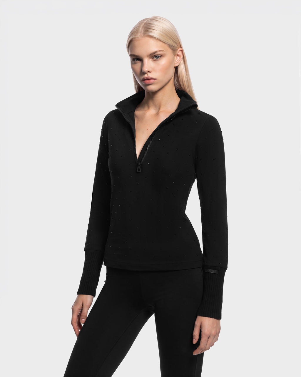 The NEVA - 8526524 Black is a black long-sleeved pullover featuring a quarter-zip collar and small stud embellishments.