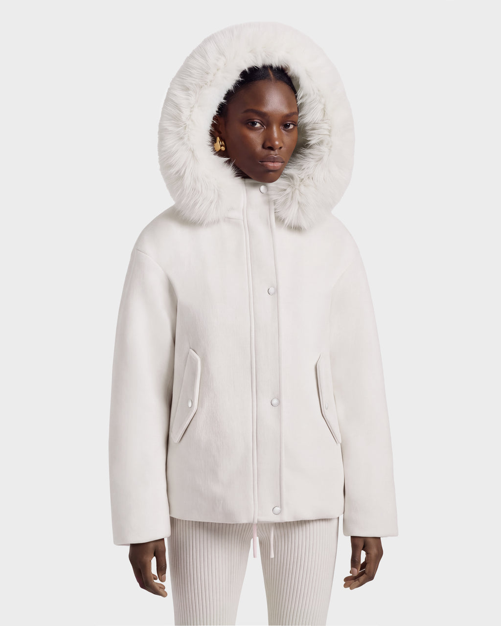 A person wears a vanilla-colored HAZEL - 8126981 wool-blend winter coat with a large, detachable faux-fur hood pulled up over their head.