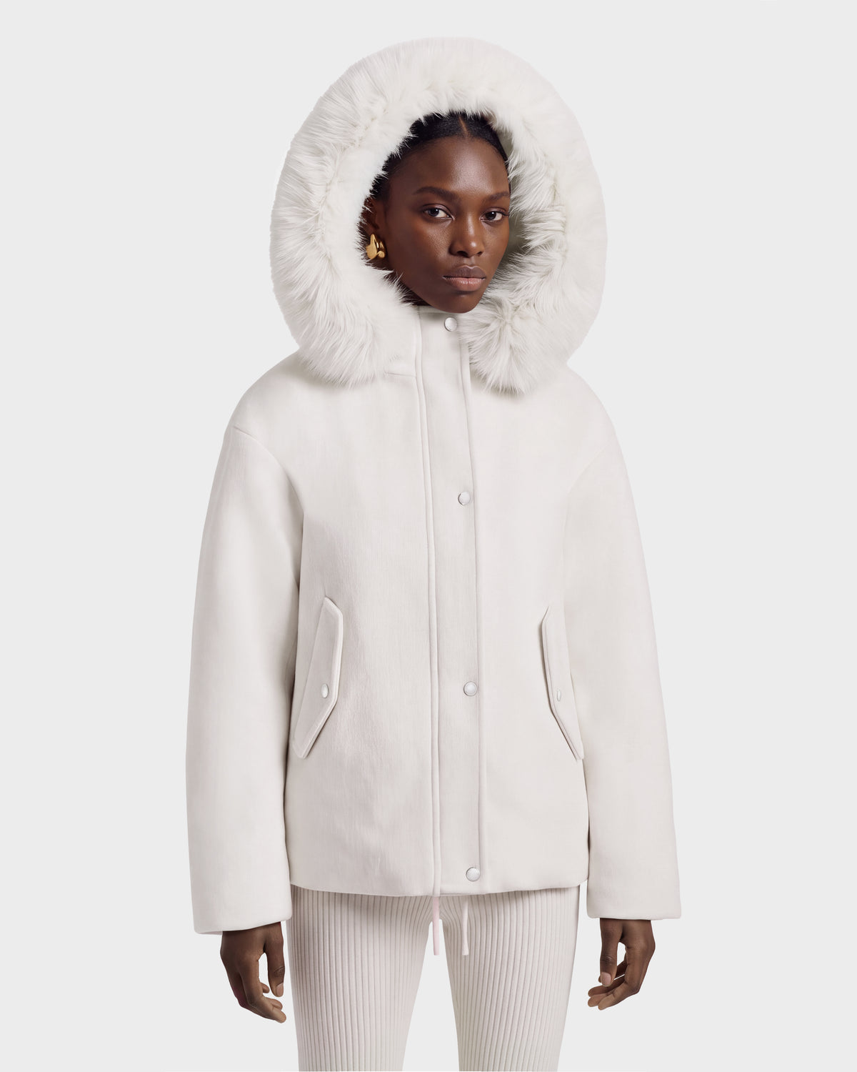 A person wears a vanilla-colored HAZEL - 8126981 wool-blend winter coat with a large, detachable faux-fur hood pulled up over their head.