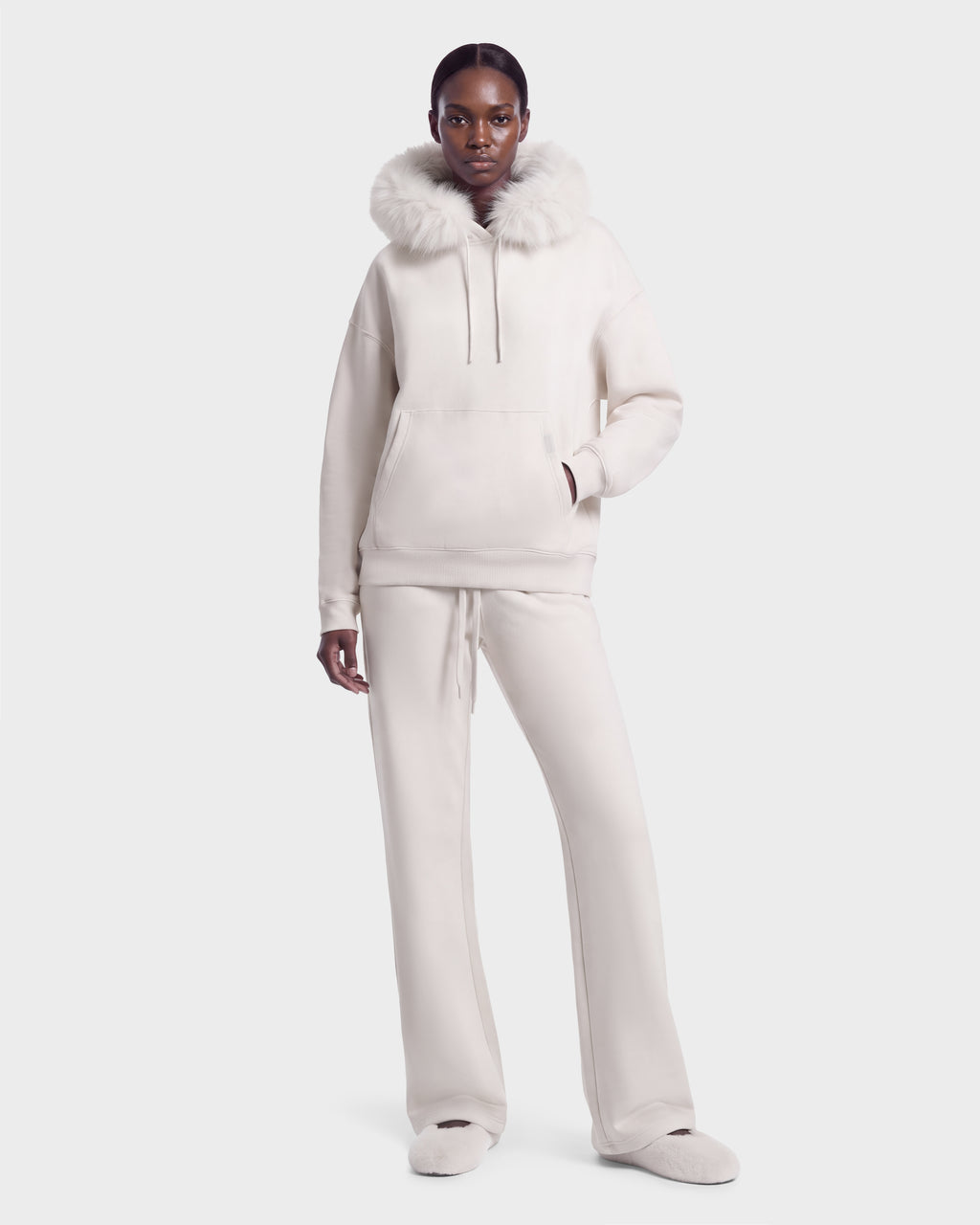 A model wears the ANGEL - 8526725 Vanilla hooded sweatshirt with a fur-trimmed hood and matching wide-leg stretch cotton sweatpants for a refined off-duty look.