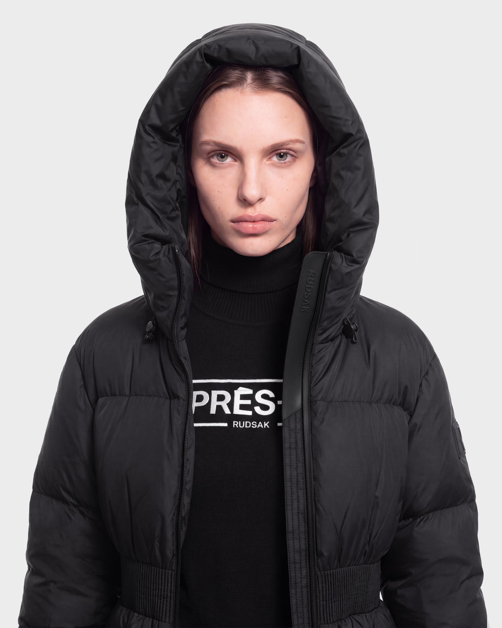 A woman wears the DIAMOND - 8126772 Black by Rudsak and a black PRÉS. Rudsak turtleneck sweater, standing facing forward against a plain light background.