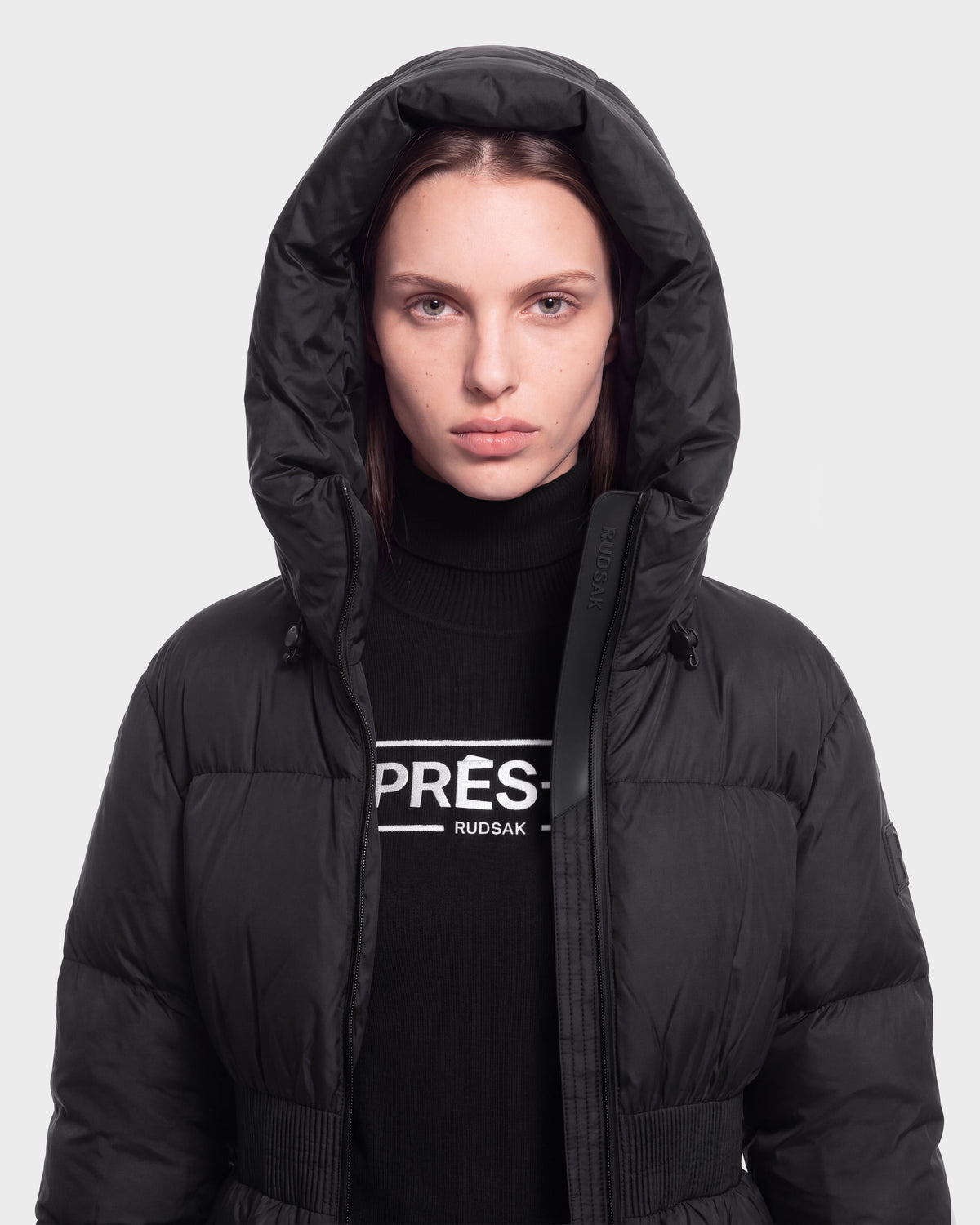A woman wears the DIAMOND - 8126772 Black by Rudsak and a black PRÉS. Rudsak turtleneck sweater, standing facing forward against a plain light background.