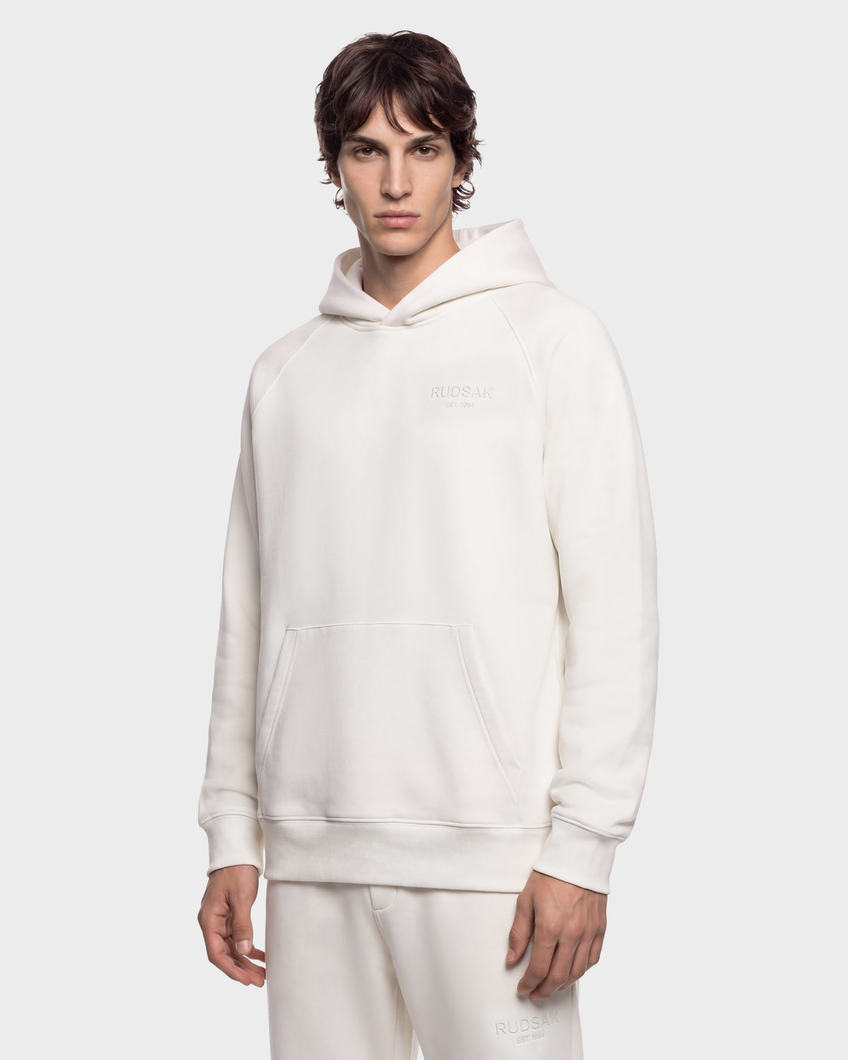 A man wearing a cream-colored BRIAR - 9525001 Vanilla M unisex hoodie with a kangaroo pocket for a casual look.