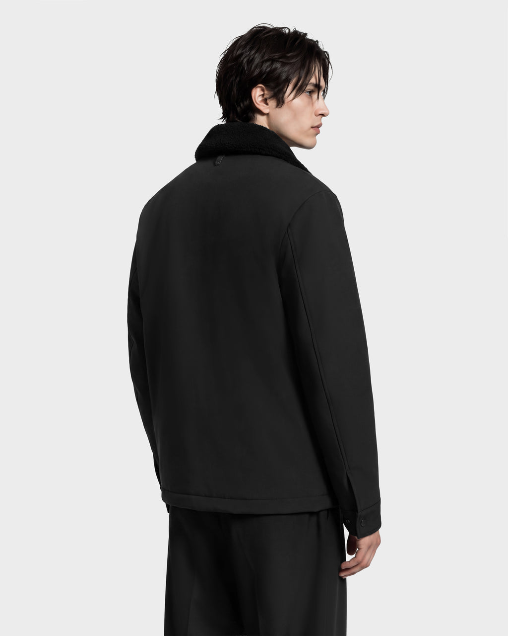 A person in profile wearing the Rudsak ANTOINE - 6126506 Black utility jacket, featuring a refined silhouette and a black faux-fur collar.