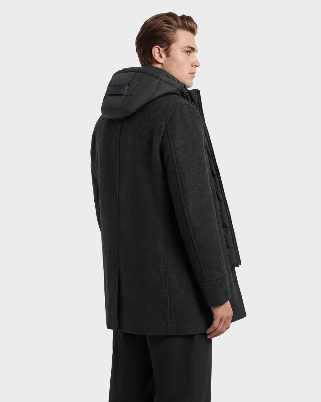 A person wearing a charcoal LUCIEN - 6126508 coat featuring a black puffer hood with duck down insulation and a zippered inner layer.