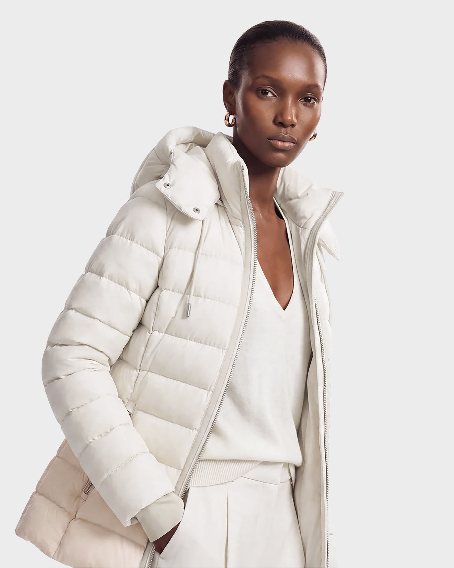 A woman wearing the Rudsak PELIN S - 8124813 Vanilla quilted jacket over a white V-neck top and light trousers, standing against a plain light background.
