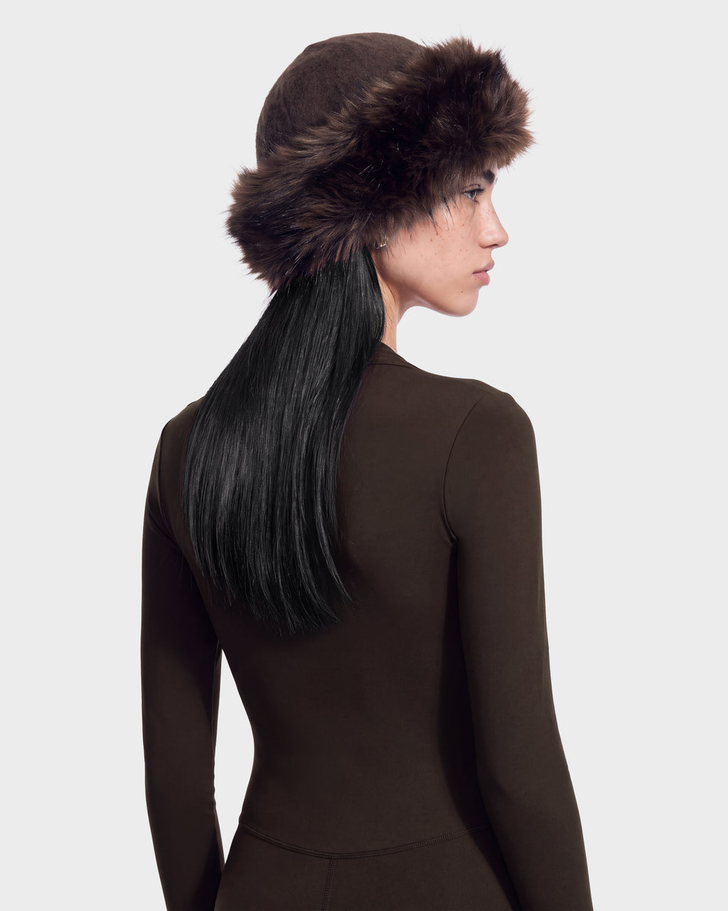 A person wearing a LORETTA W - 8426510 Espresso RUDSAK winter hat, featuring a brown design with a faux fur brim.