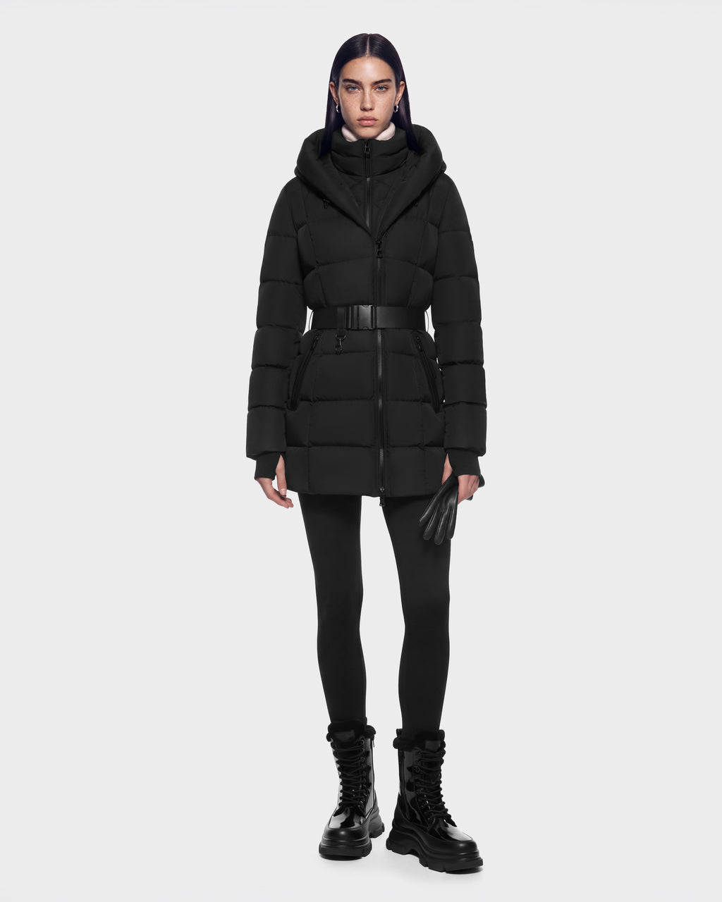A model wearing a black RUDSAK TAYLOR M - 8125965 Black belted puffer coat with a hood, black leggings, leather gloves, and platform boots.
