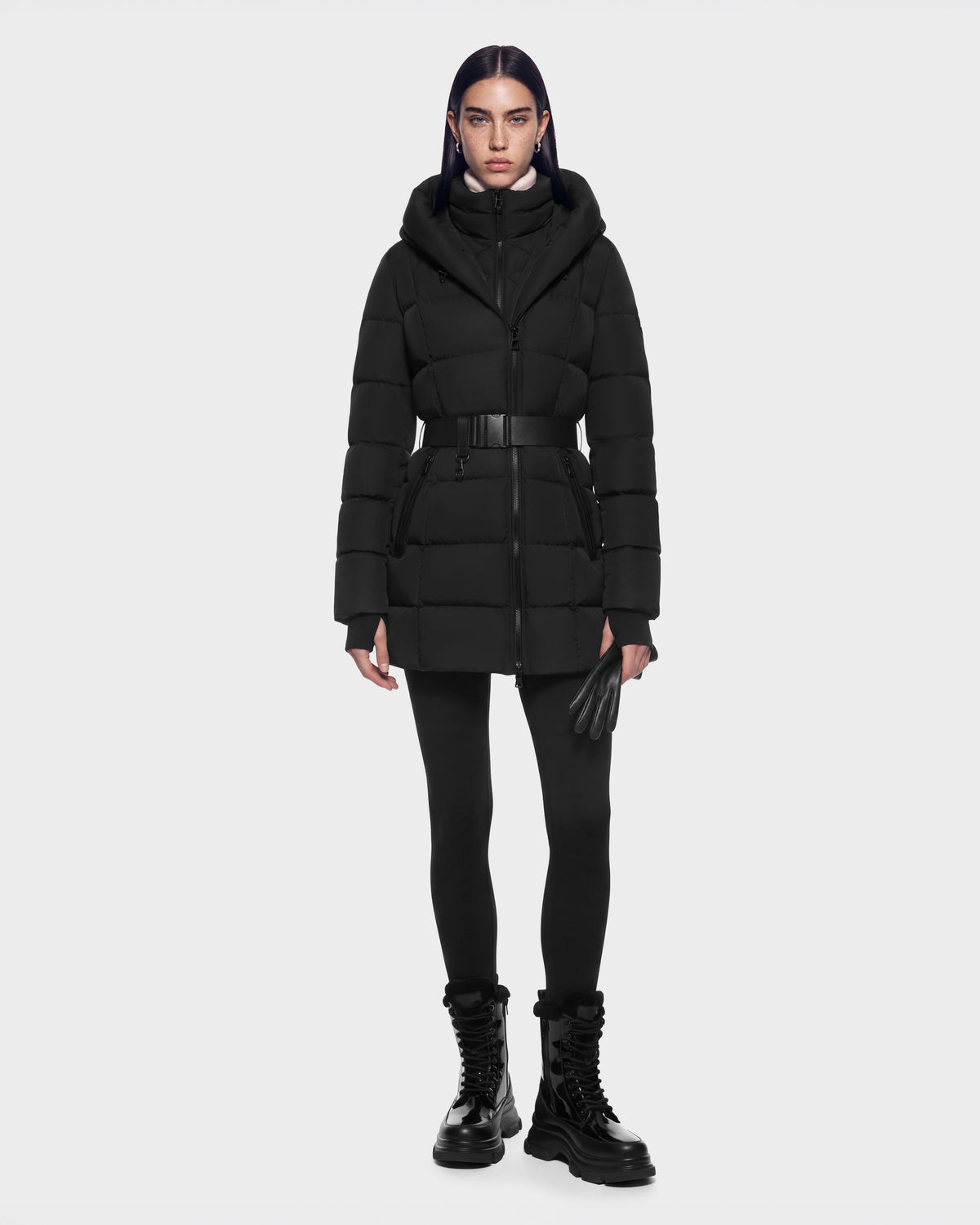 A model wearing a black RUDSAK TAYLOR M - 8125965 Black belted puffer coat with a hood, black leggings, leather gloves, and platform boots.