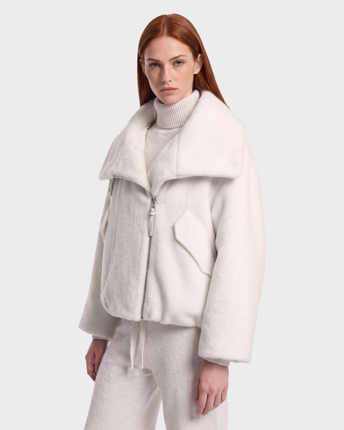 A model wearing a Rudsak ZARIA - 8126999 Vanilla off-white faux-fur collar winter puffer over a matching turtleneck sweater and trousers.