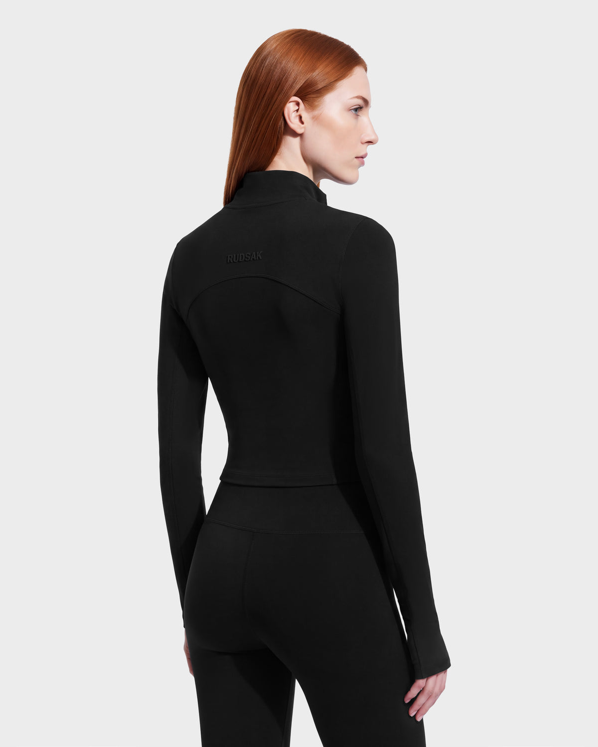 A person seen from behind wearing an ANITA - 8526579 Black, long-sleeved, performance-inspired athletic zip-up jacket with a mock neck and a cropped silhouette.