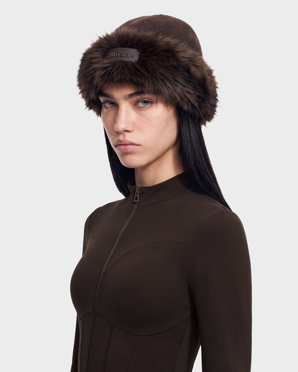 A person wearing a dark brown zip-up long-sleeved top and a matching LORETTA W - 8426510 Espresso faux-fur trimmed beanie.