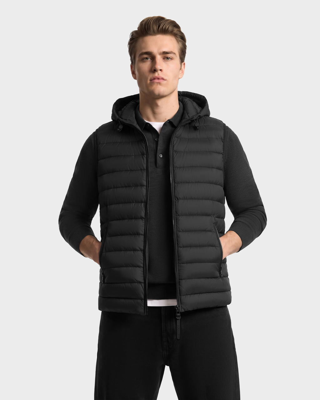 A man wearing a Rudsak BRUNO - 6126716 Charcoal quilted hooded vest over a matching long-sleeved polo shirt.