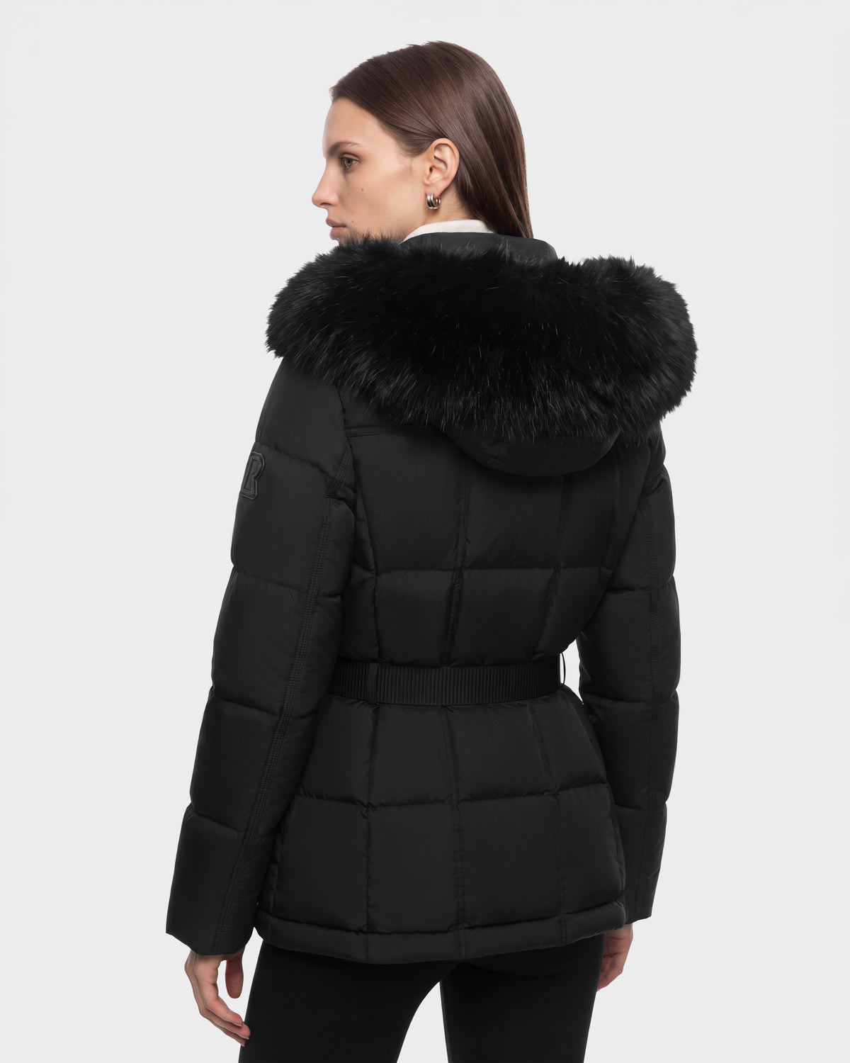 A woman wearing a black, belted, quilted GRACE FF - 8126535 Black puffer jacket with a fur-trimmed hood.