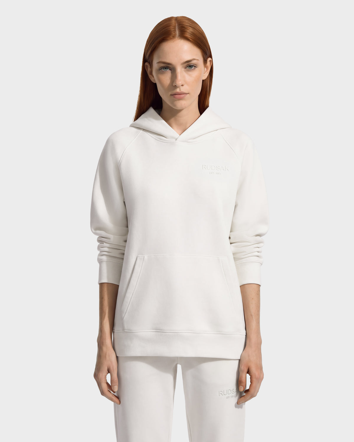 A person wearing a BRIAR - 9525001 Vanilla W unisex, premium cotton blend white pullover hoodie featuring a hood, long sleeves, and a front kangaroo pocket.