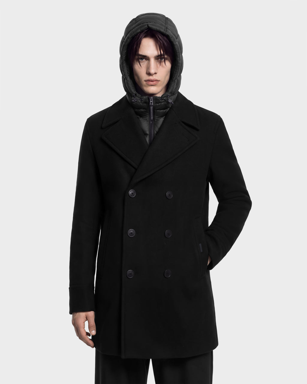 A person wearing a black Rudsak LUCIEN - 6126508 double-breasted pea coat over a hooded quilted jacket with duck down insulation.