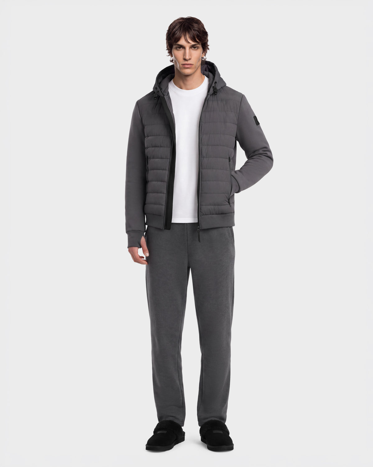 A man wears a DEE MAT - 6124028 Grey urban jacket with quilted paneling over a white t-shirt, paired with matching grey sweatpants and black slip-on shoes.