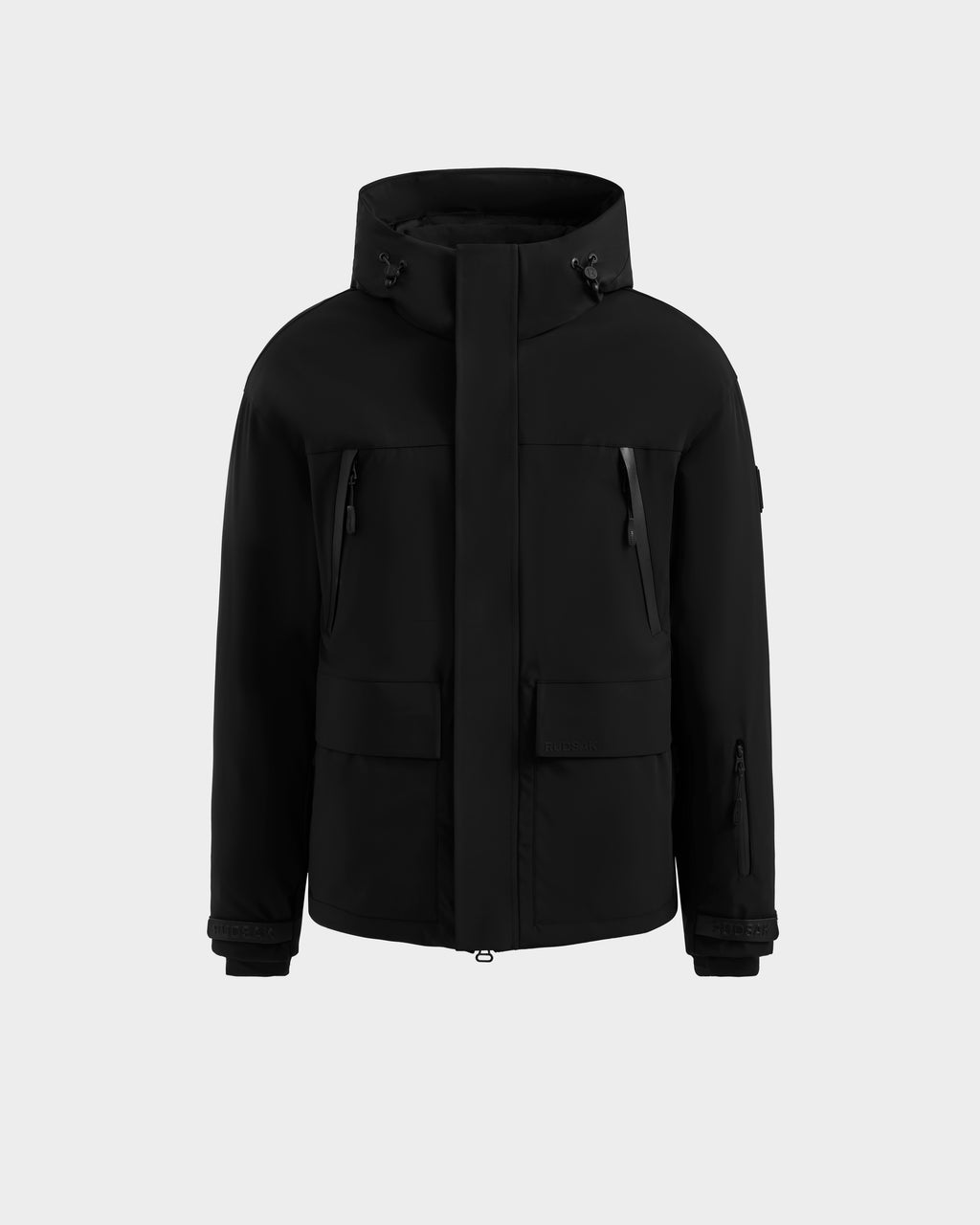 The Rudsak ETHAN - 6125589 Black men’s ski jacket features zippered chest pockets, flap front pockets, and adjustable cuffs, shown against a plain light gray background.