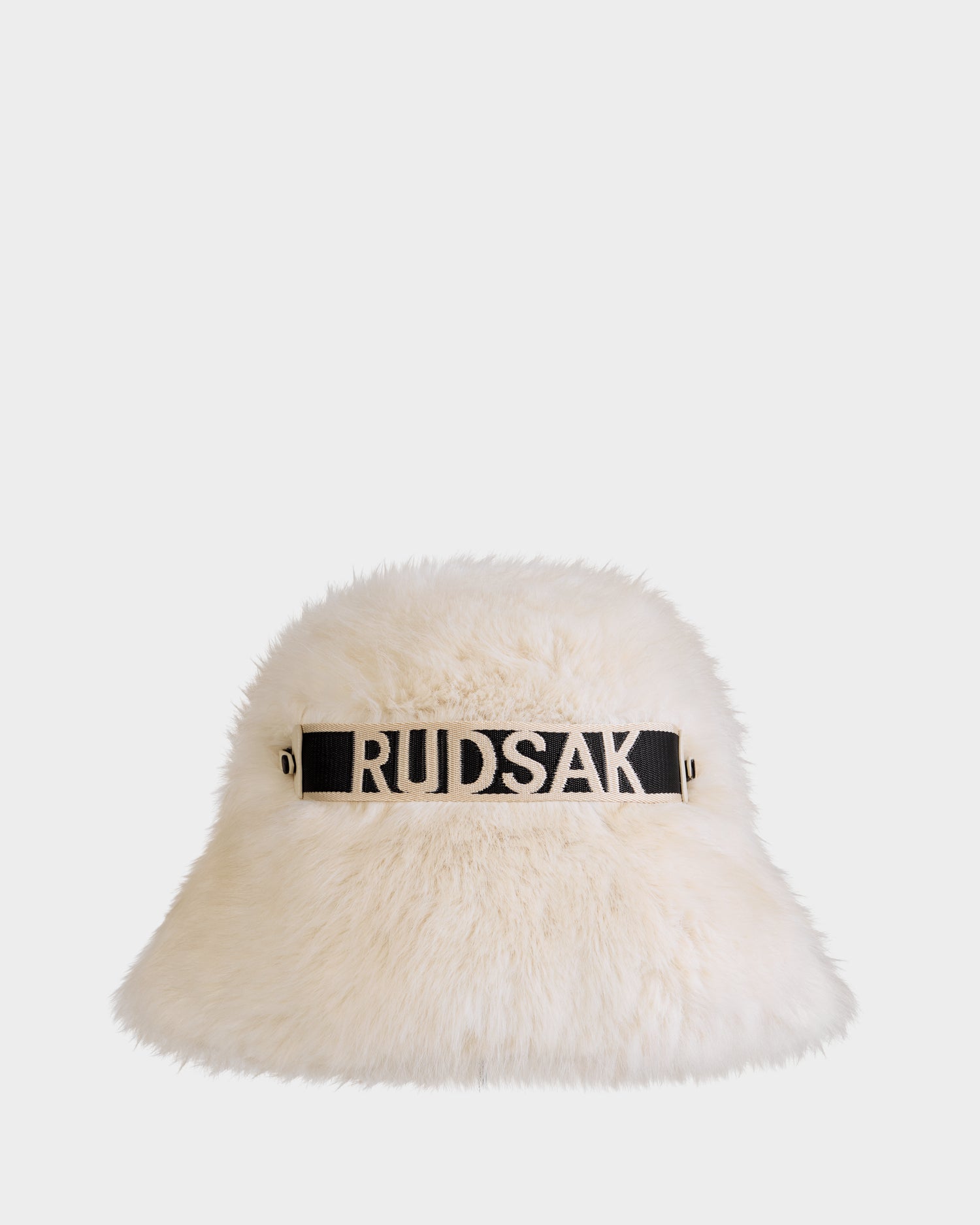 The ROMINA - 8425545 Vanilla by Rudsak is a cream faux fur women's bucket hat with a black band and bold white RUDSAK logo—a chic and cozy winter accessory to elevate your cold-weather style.
