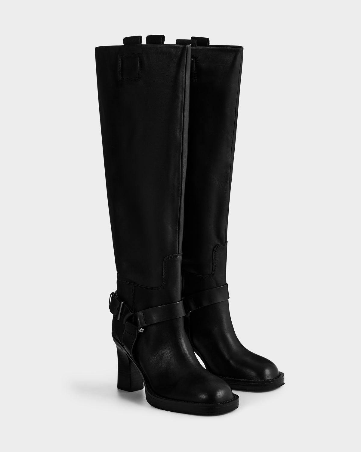 The ROSSEY - 8225574 Black boots by Rudsak feature tall black leather, a rounded toe, block heel, and harness strap detailing at the ankle, displayed against a plain light background.