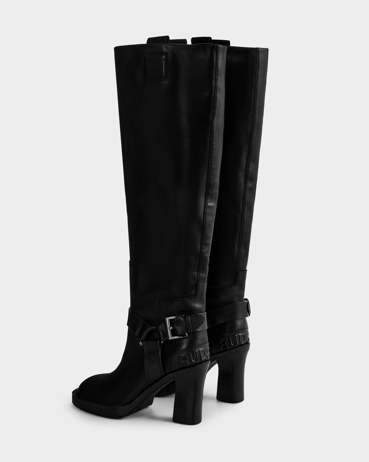 A pair of ROSSEY - 8225574 Black tall leather heeled boots by Rudsak, featuring decorative straps and buckles at the ankles, displayed against a plain light background.