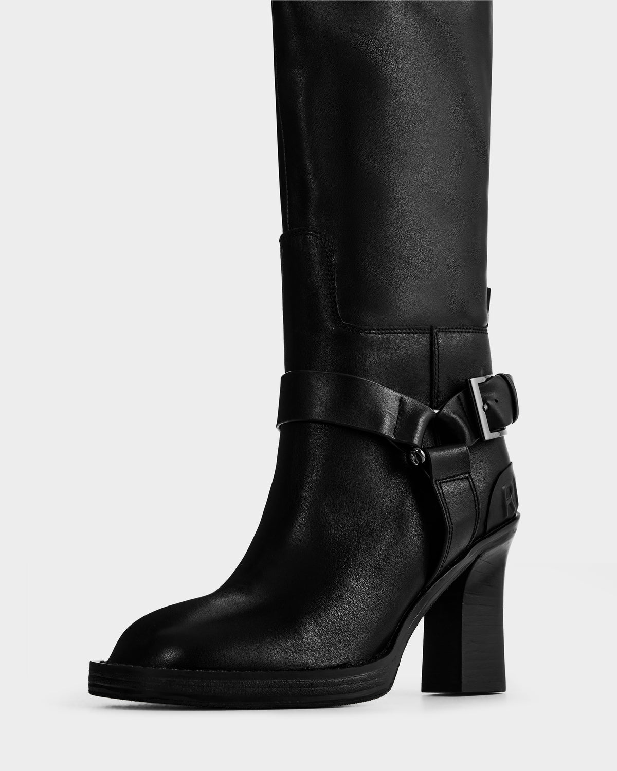 The Rudsak ROSSEY - 8225574 Black is a knee-high black leather boot with a chunky high heel, decorative ankle strap, and metal buckle detail, shown against a plain light background.