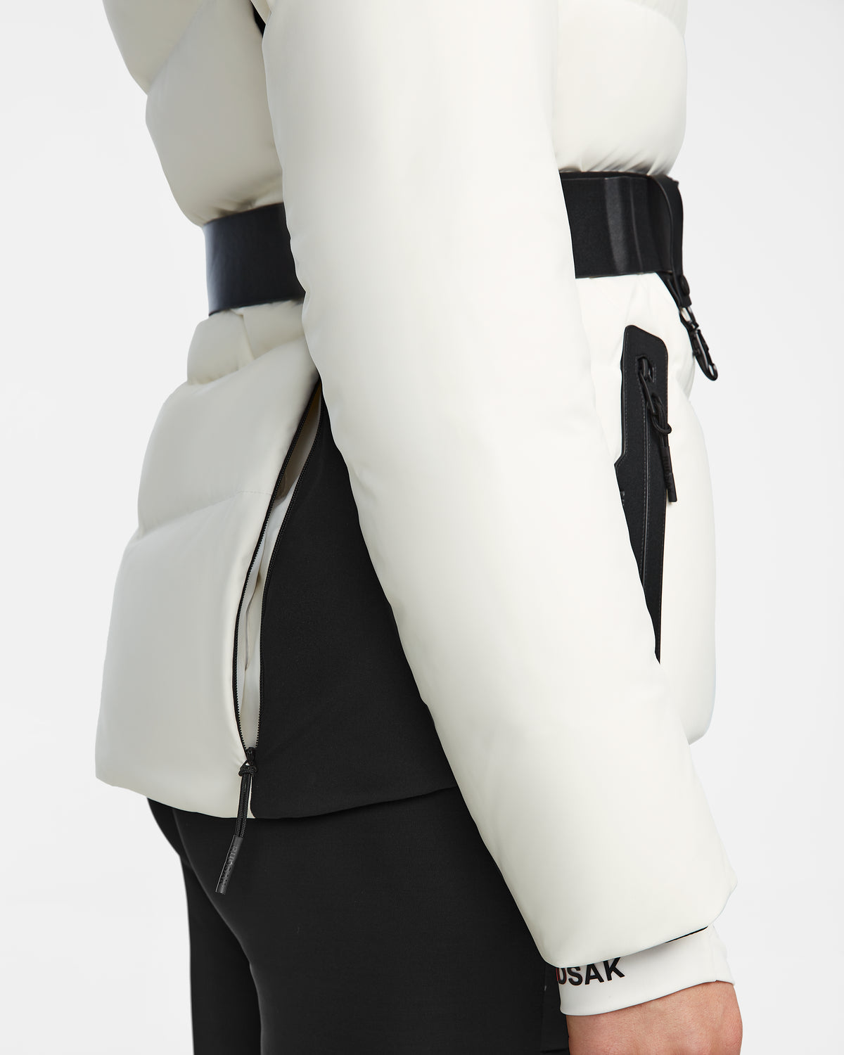 A close-up of the Rudsak ALAIA - 8124816 Iceland ski jacket with black accents, zippers, side pocket, and waist belt detail, paired with black pants.