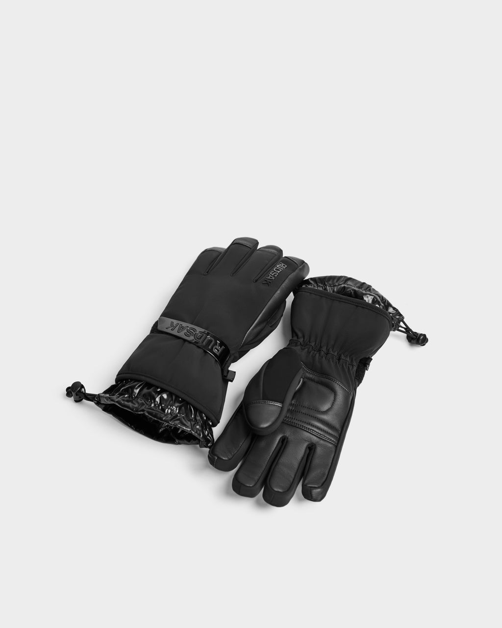A pair of Rudsak APLEN - 6424505 Black insulated ski gloves with adjustable wrist cuffs, one palm up and one palm down, displayed on a plain light gray background.