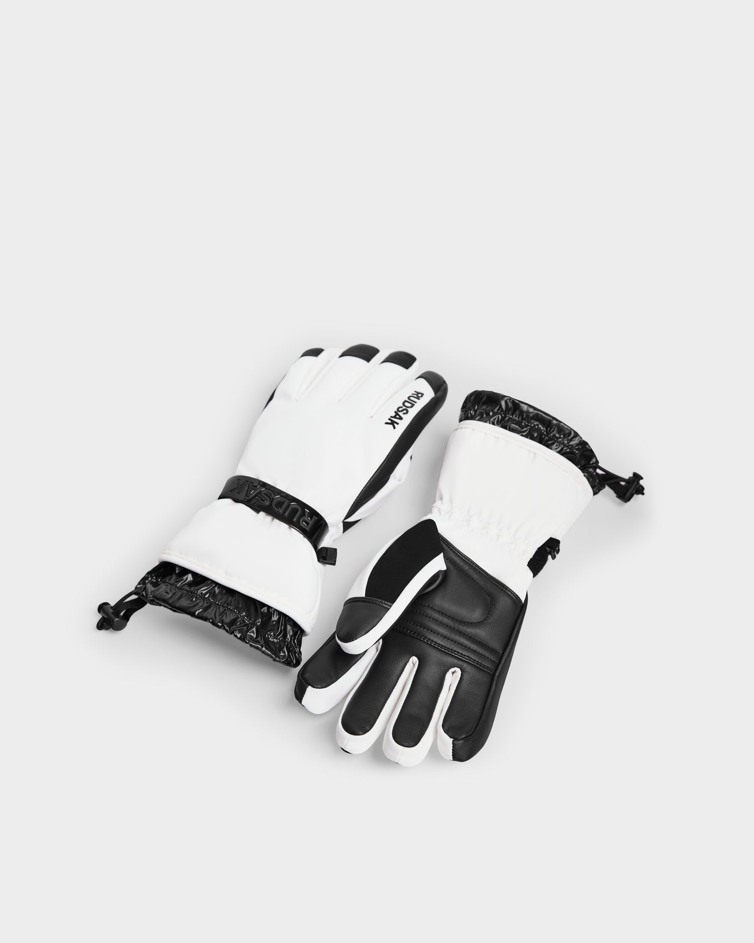 The Rudsak APLEN - 6424505 Optic White ski gloves feature black and white insulation, waterproof zippers, and adjustable wrist straps. Shown on a white background with one glove palm up and the other palm down.