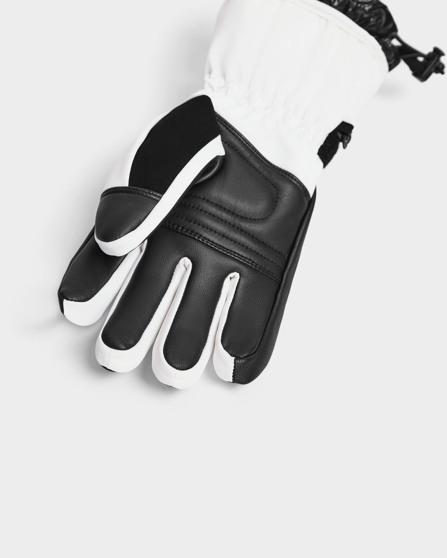 A close-up of the Rudsak APLEN - 6424505 Optic White insulated ski glove featuring reinforced knuckles, a black palm, waterproof zippers, and an adjustable wrist strap, displayed on a white background.