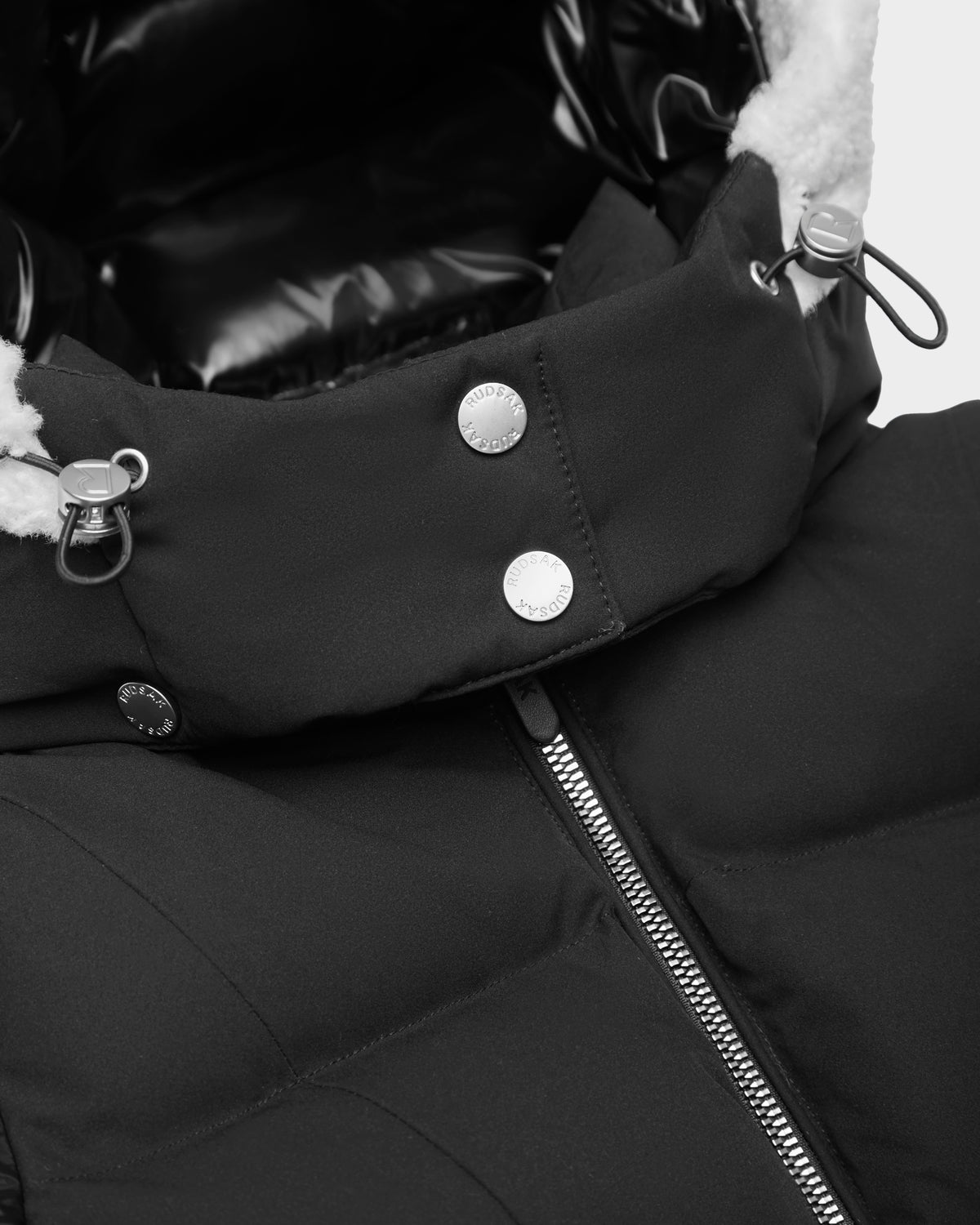 The Rudsak AUDREY K - 0124504 Black girls’ down puffer jacket has a shiny zipper, metal snaps, adjustable hood drawstrings, and soft white fleece lining. Its water-repellent design keeps her warm and cozy in any weather.