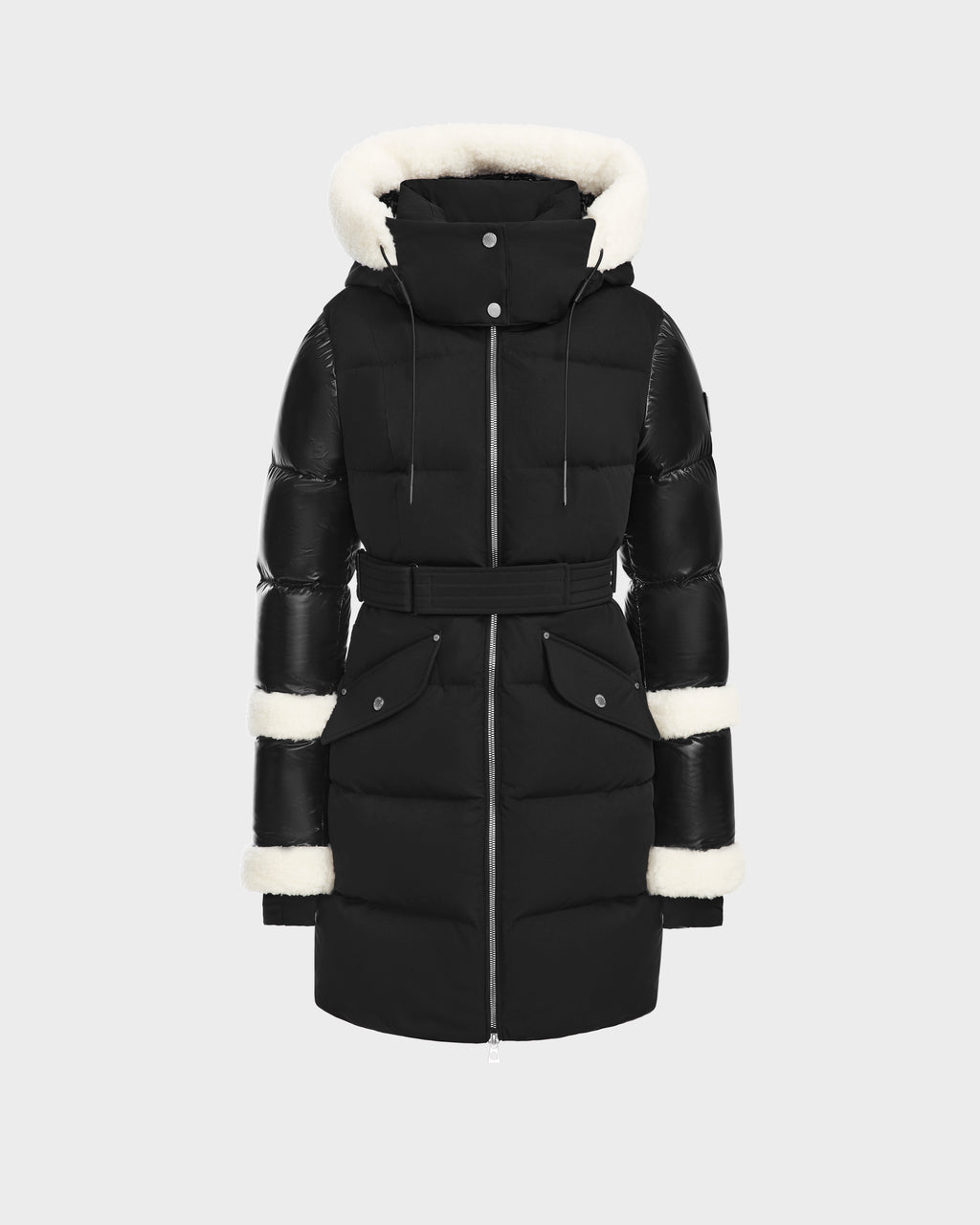 The Rudsak AUDREY L - 8124585 Black/Iceland is a knee-length down puffer jacket with a belted waist, front zipper, snap buttons, and white faux fur trim on the hood, cuffs, and mid-sleeves, shown against a plain light background.