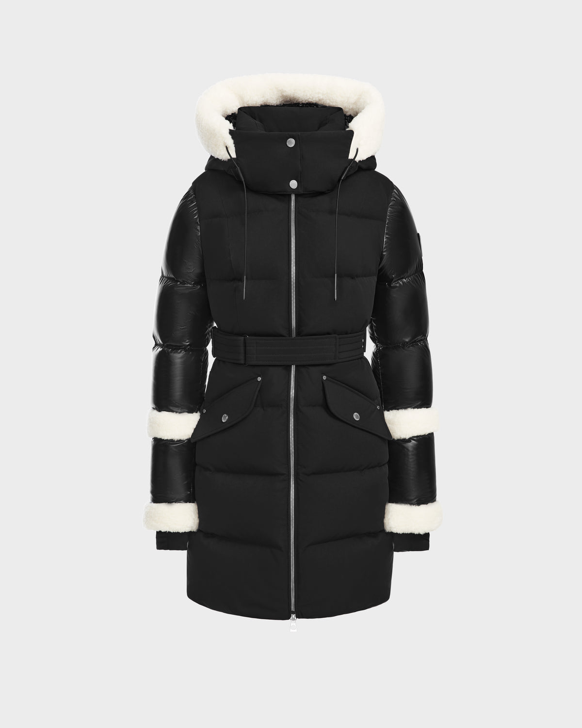 The Rudsak AUDREY L - 8124585 Black/Iceland is a knee-length down puffer jacket with a belted waist, front zipper, snap buttons, and white faux fur trim on the hood, cuffs, and mid-sleeves, shown against a plain light background.