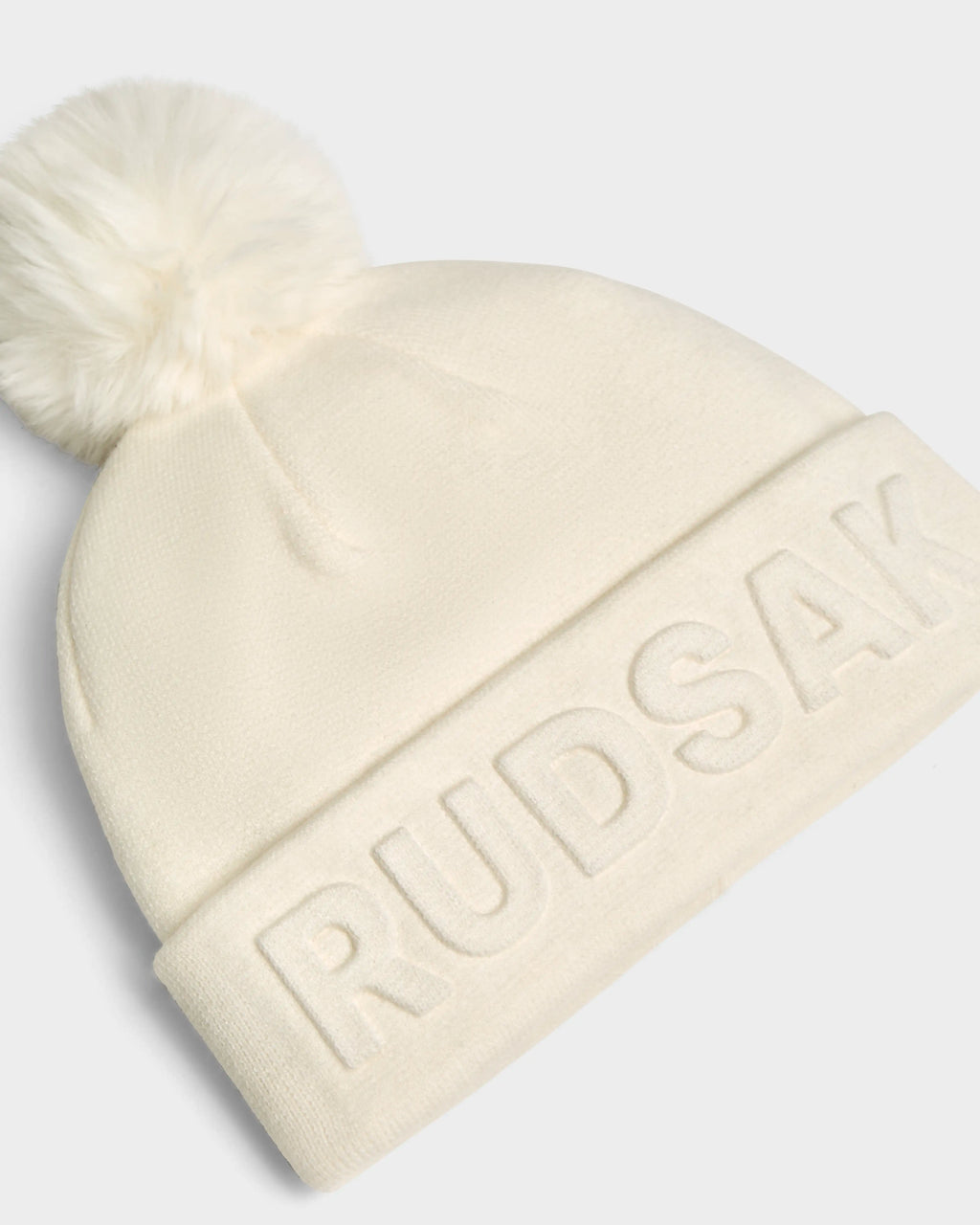 The CERRY - 9423508 Iceland is a white unisex knit tuque featuring a fluffy removable pom pom and Rudsak branding embroidered on the turned-up brim.