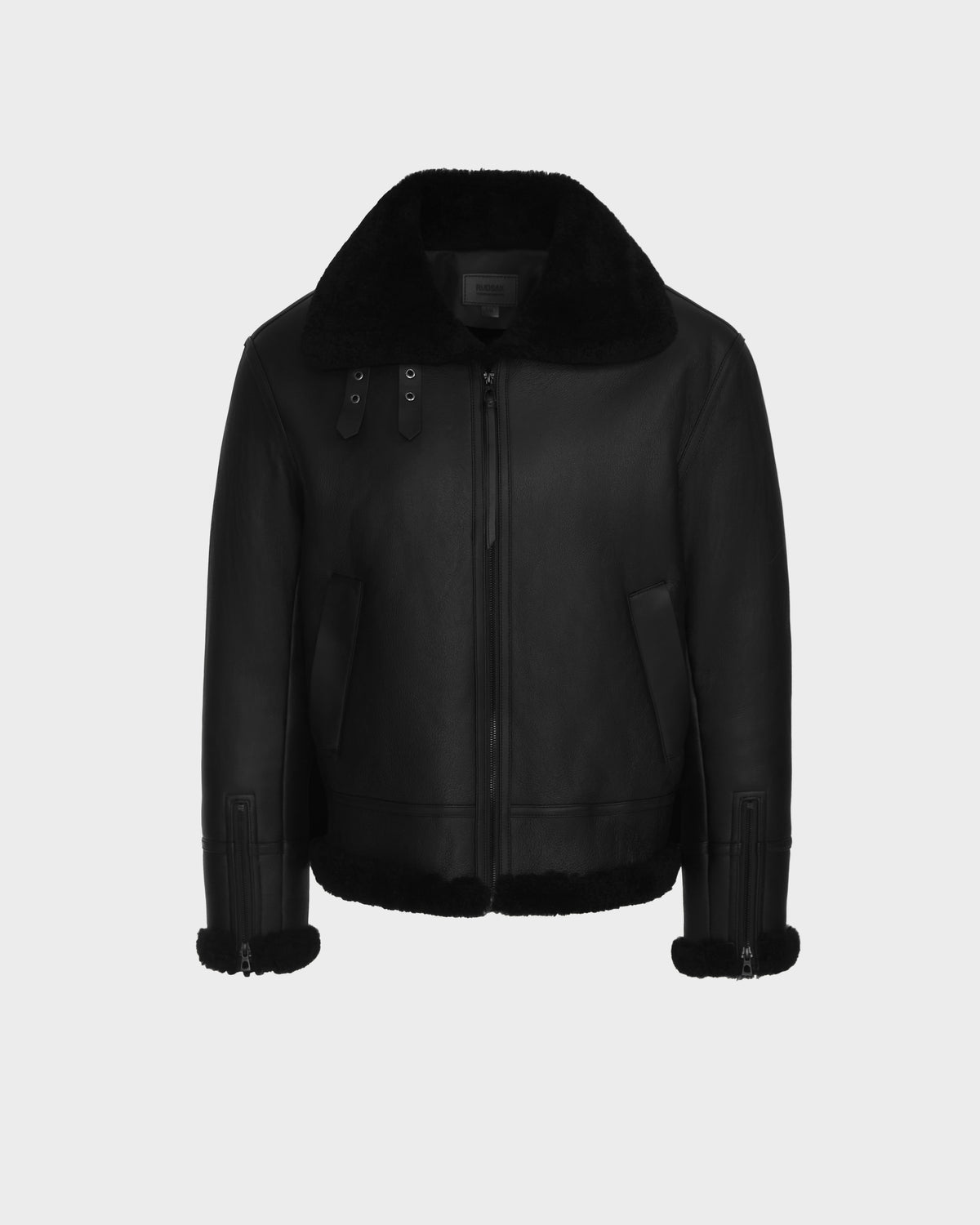 The Rudsak CONOR - 6124596 Black is a black shearling jacket with a large collar, front zipper, two side pockets, and buckle details on the collar and cuffs, displayed on a plain light gray background—perfect for winter.