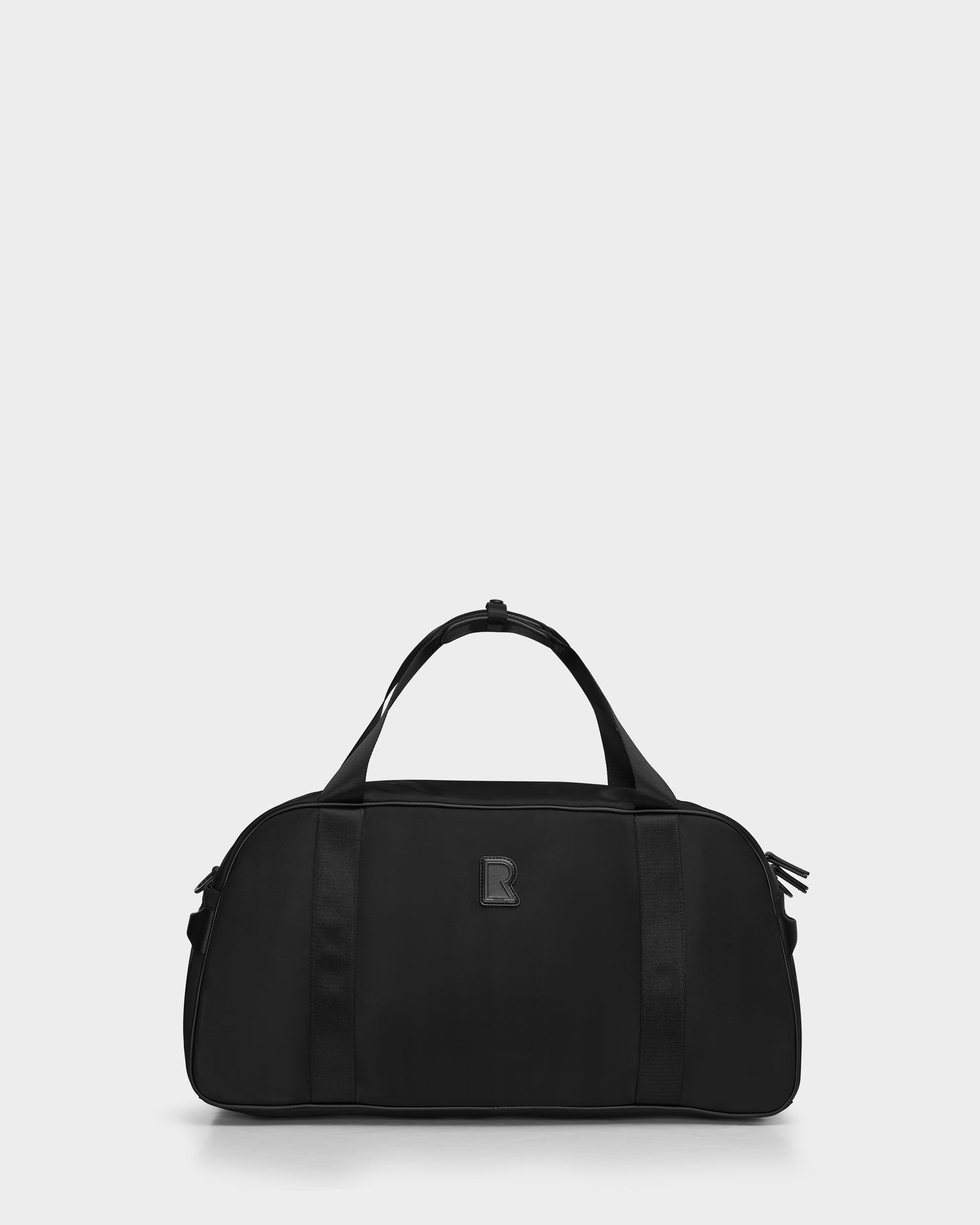 The Rudsak DUFF - 9324506 Black is a unisex duffel bag featuring two handles, a zipper closure, and a subtle rectangular front logo, shown on a light gray background—perfect for travel and any adventure.