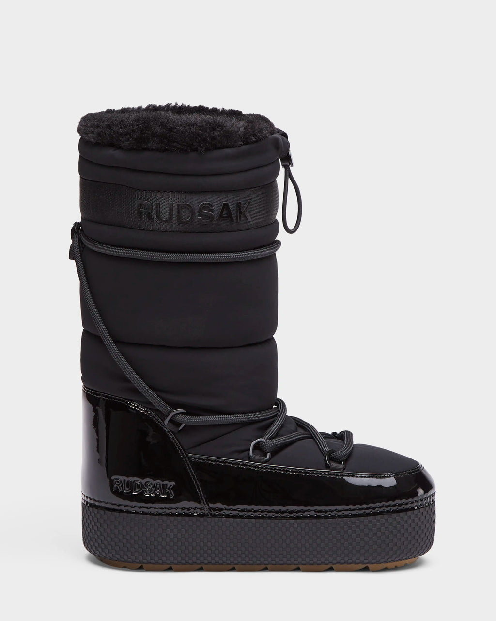 The FARAH L - 8224542 Black by Rudsak is a women’s black, high-rise winter boot with a quilted upper, faux fur lining, patent leather lower section, laces, thick sole, water-repellent finish, and side RUDSAK branding for stylish warmth.