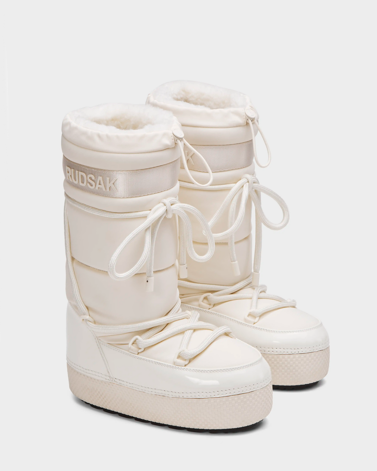 A pair of Rudsak FARAH L - 8224542 Iceland off-white faux fur lined boots with thick soles, lace-up fronts, and plush lining is displayed on a plain white background.