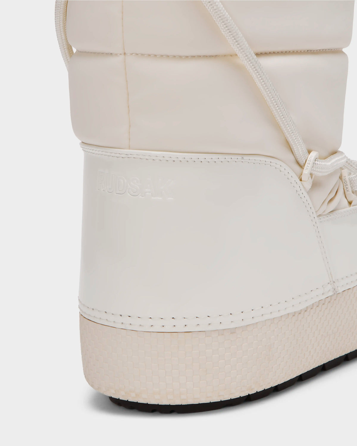 Close-up of the heel and side of the white FARAH L - 8224542 Iceland women’s winter boot by Rudsak, featuring a textured sole, visible stitching, faux fur lining, and RUDSAK embossed on the side.