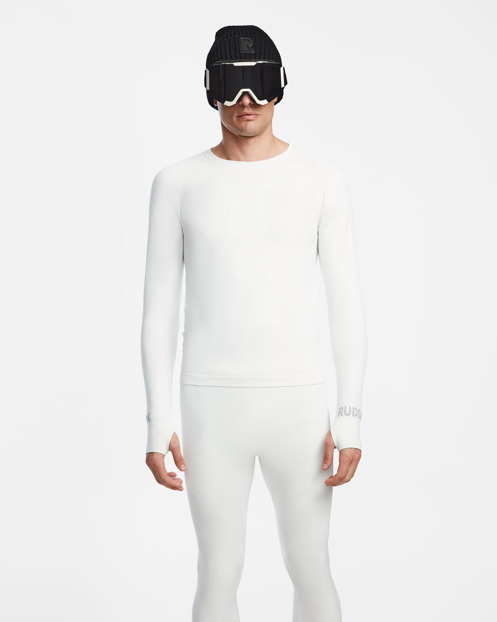 A person wears the fitted, all-white Rudsak FRANC - 6524541 Iceland men’s thermal underwear with white ski goggles and a black beanie, standing against a white background. This sleek set is the ideal skiing underlayer for a modern look.