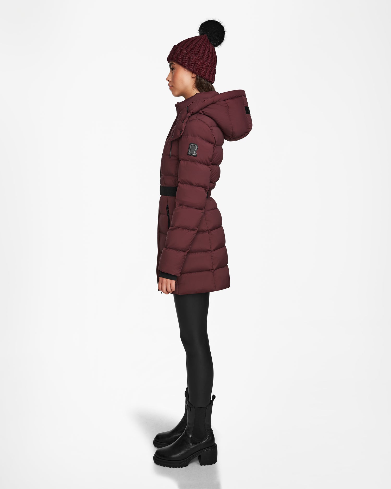 A woman in the Rudsak FRIDA M - L124524 Wine, a quilted down jacket with a removable hood.