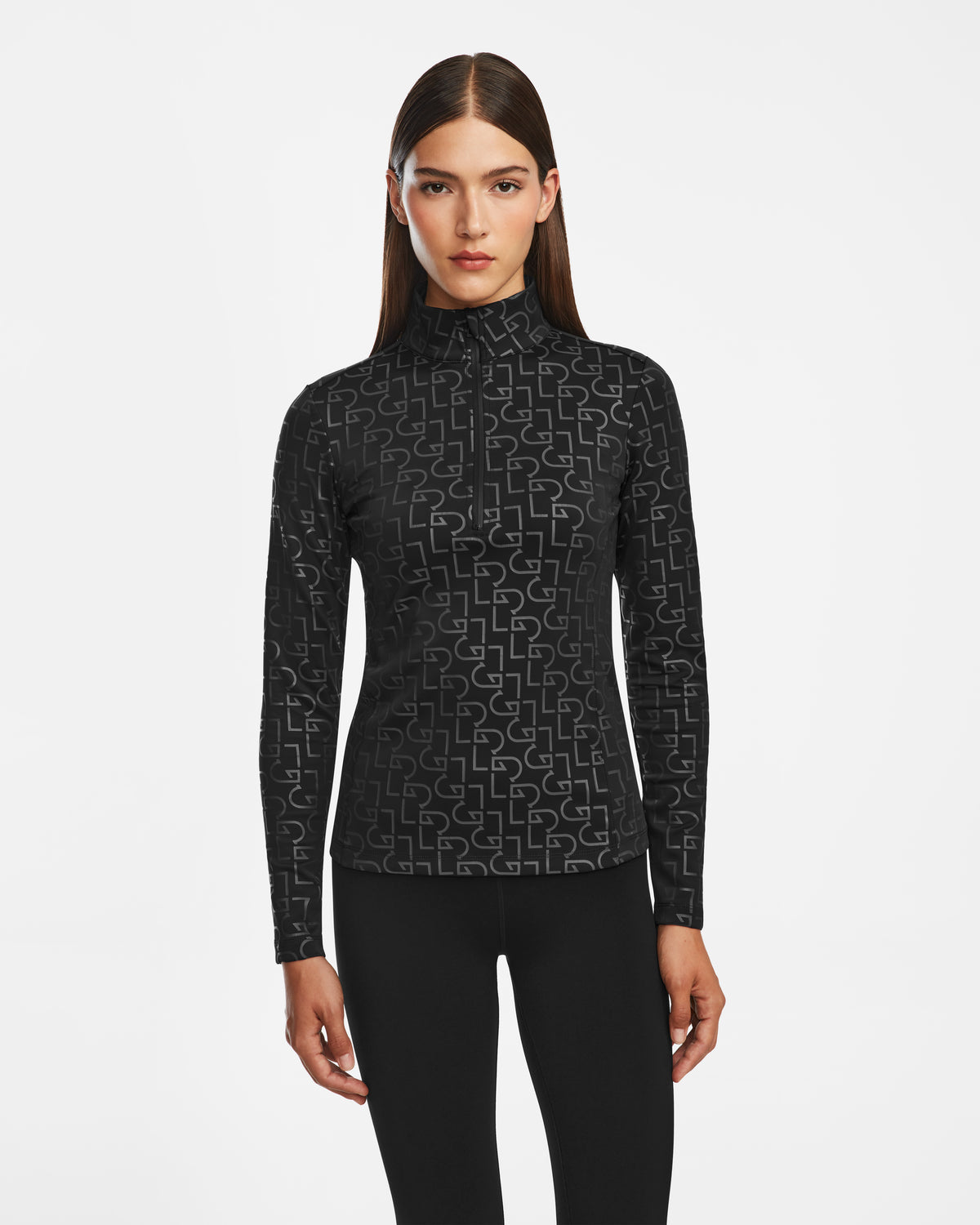 A woman with straight brown hair models the Rudsak GASIA - 8524567 Black women’s stretch active top featuring a geometric pattern, paired with black pants, against a plain white background.