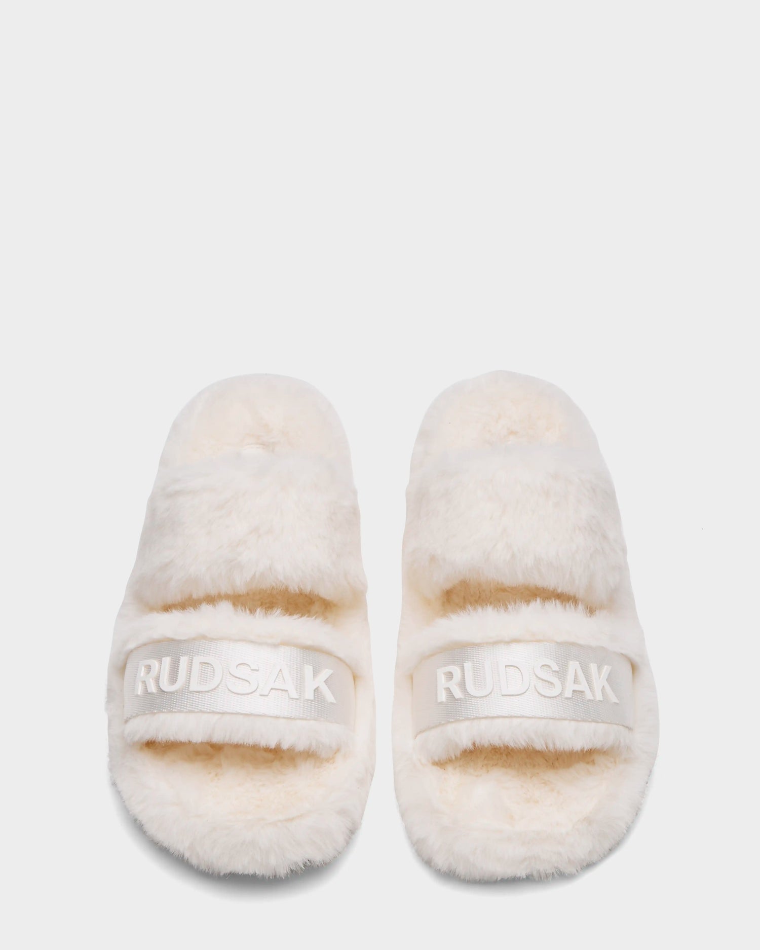 The Rudsak GEMA - 8223510 Iceland women's slipper slides feature thick, fluffy faux fur straps with "RUDSAK" embroidered in white across each band, shown on a plain white background.