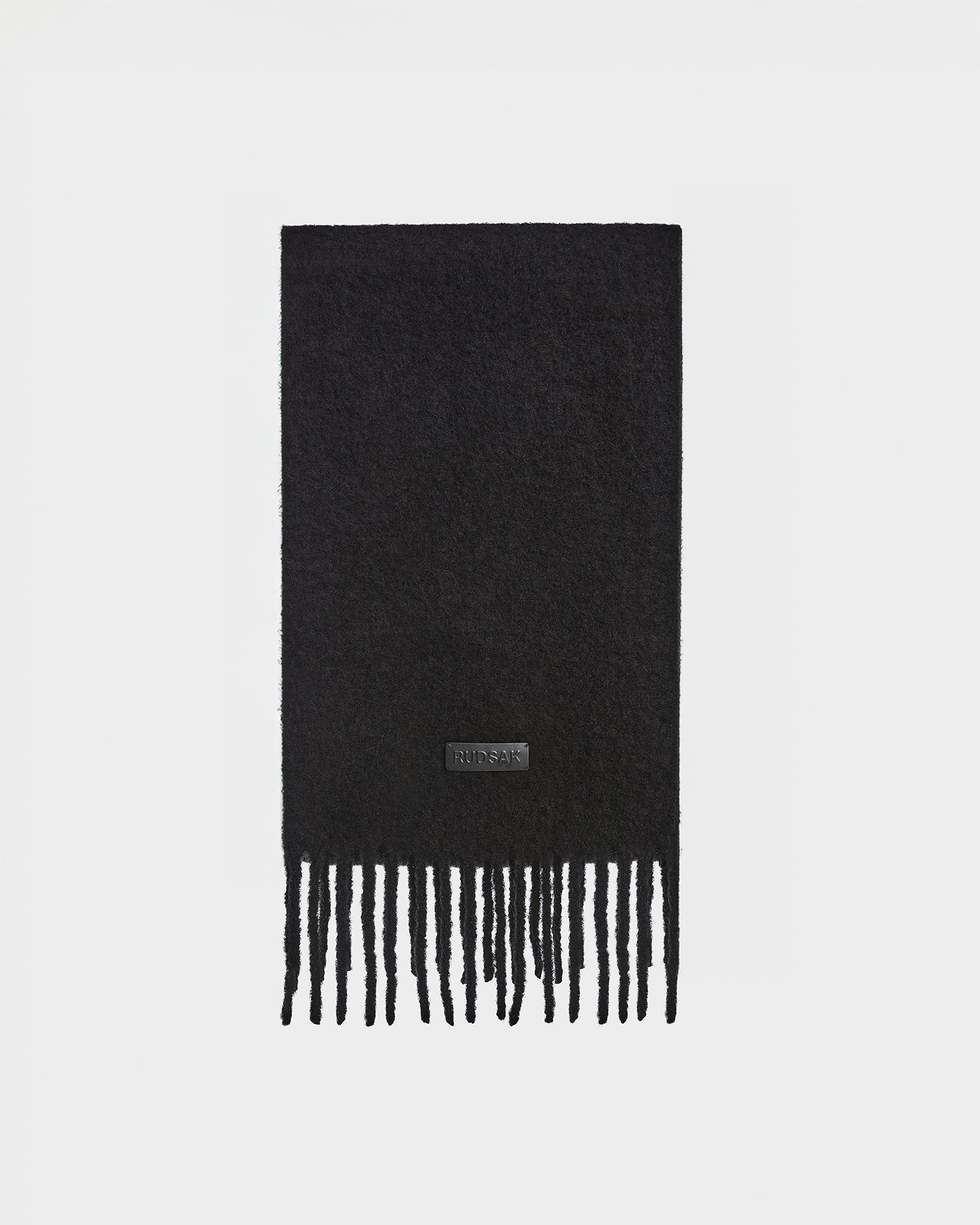 The HAILEE - 9424507 Black unisex scarf by Rudsak features a fuzzy alpaca wool texture, long thin fringe, and a small KIDSACK patch—making it a cozy winter accessory.