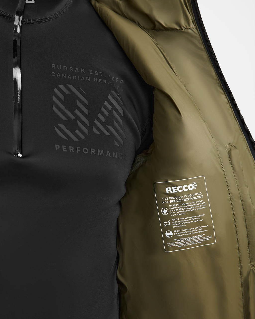 A close-up of the Rudsak HANS - 6124518 Loden Green men’s down ski jacket, partially unzipped to show a performance logo on a shirt and a RECCO tag on the olive-green wind and water-resistant lining.