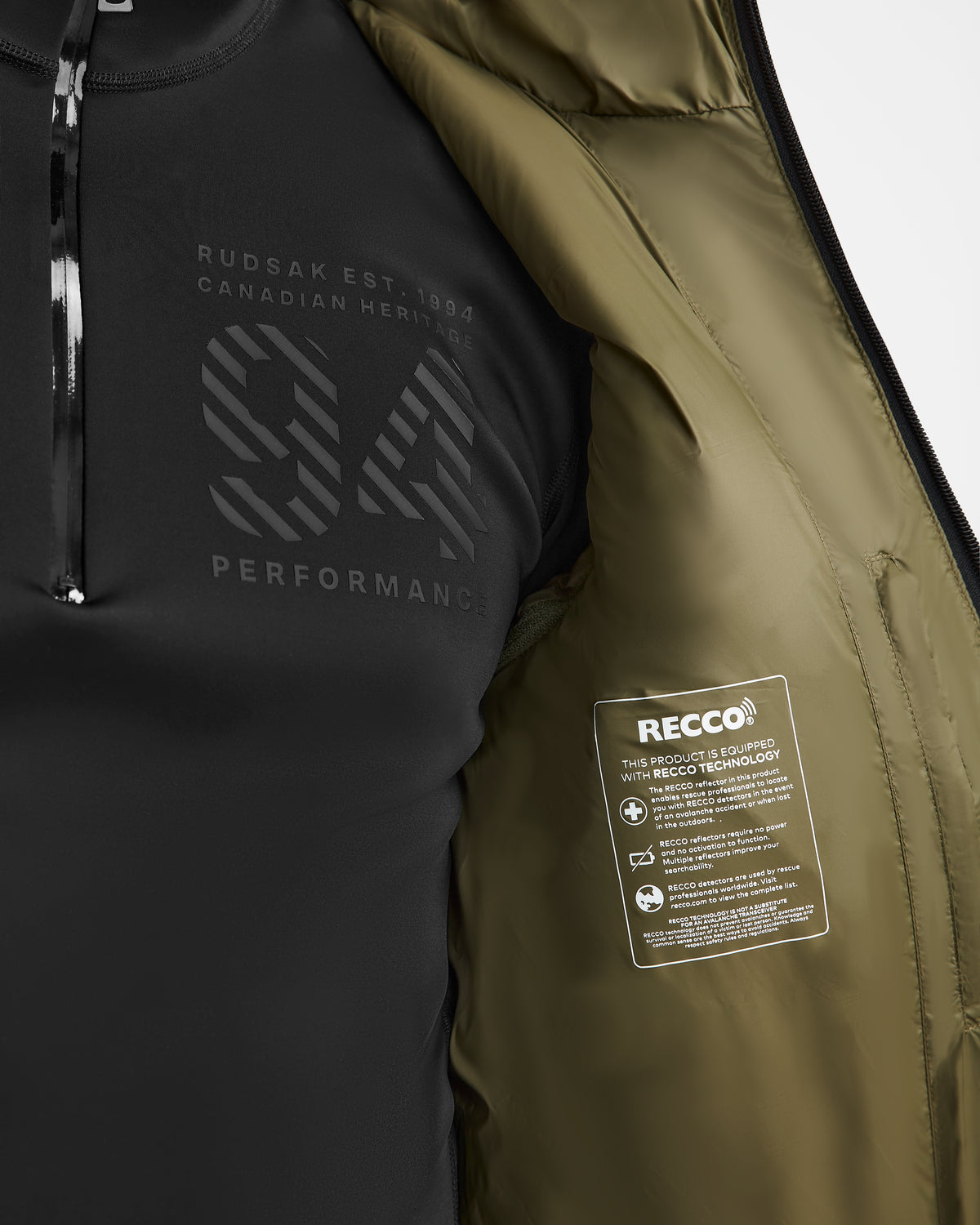 A close-up of the Rudsak HANS - 6124518 Loden Green men’s down ski jacket, partially unzipped to show a performance logo on a shirt and a RECCO tag on the olive-green wind and water-resistant lining.
